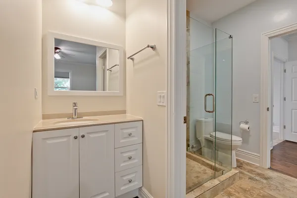 a bathroom with a granite countertop sink two mirror and shower