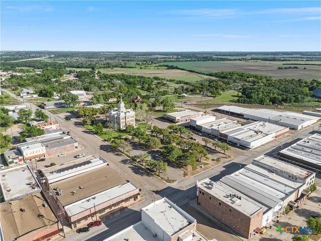 an aerial view of a city with lots of residential buildings and ocean view in back