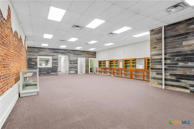 a view of an empty room with furniture and windows