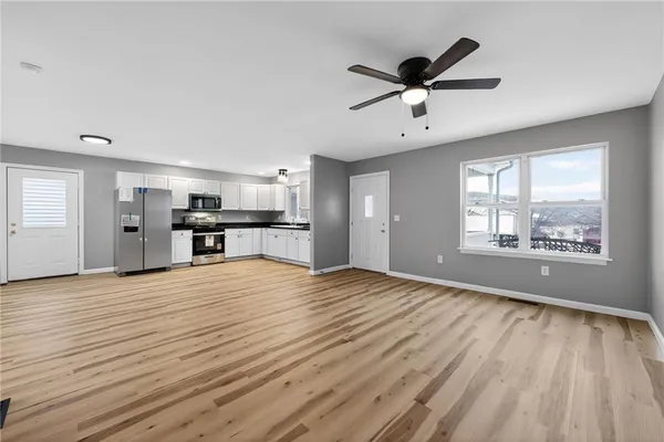 a view of an empty room with a window and wooden floor