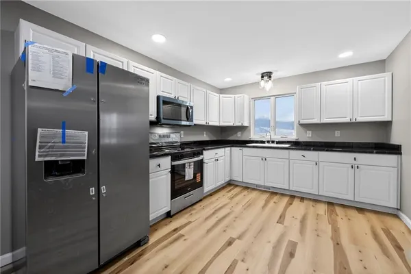 a kitchen with granite countertop a refrigerator stove top oven and sink