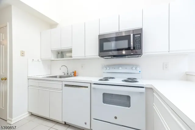 a kitchen with stainless steel appliances granite countertop white cabinets a sink and a stove