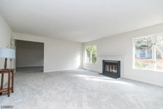 an empty room with windows and fireplace