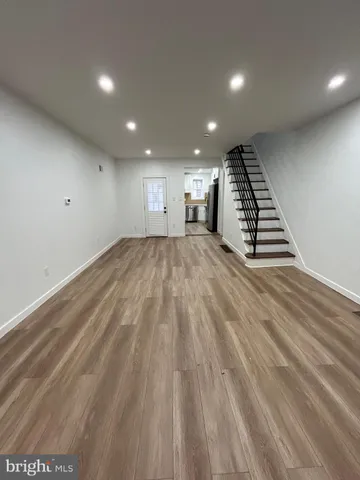 an empty room with wooden floor staircase and windows