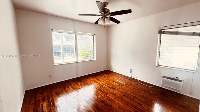a view of an empty room with window and wooden floor