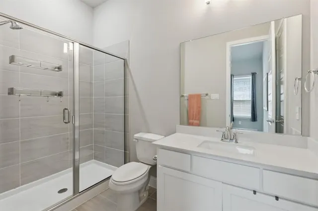 a bathroom with a shower sink mirror and toilet
