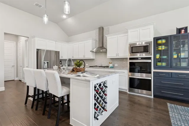 a kitchen with kitchen island granite countertop a sink cabinets and stainless steel appliances