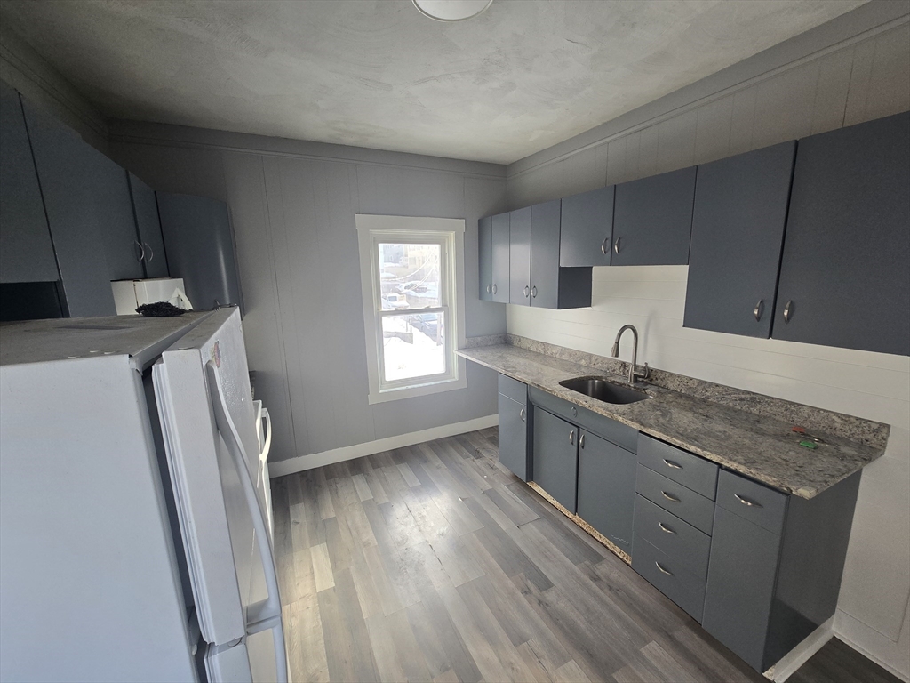 351 Tecumseh Street, Unit 2 Fall River, MA 02721 - Photo 8 of 14 a kitchen with granite countertop a sink a stove a refrigerator and wooden floor