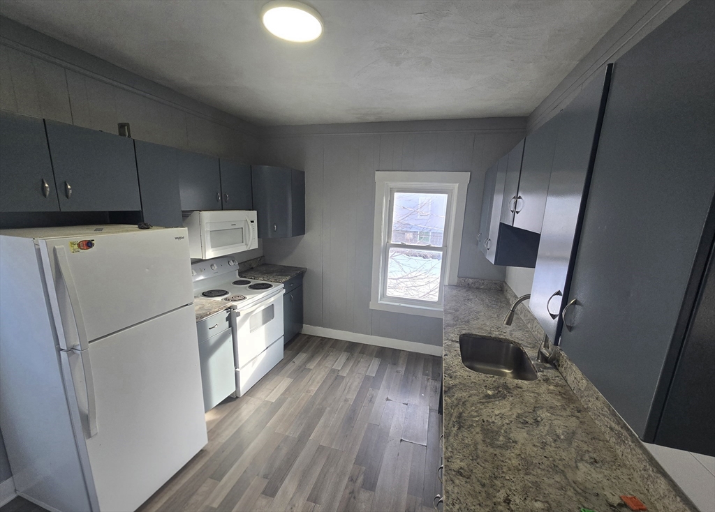 351 Tecumseh Street, Unit 2 Fall River, MA 02721 - Photo 9 of 14 a kitchen with a refrigerator a stove top oven a sink and dishwasher with wooden floor