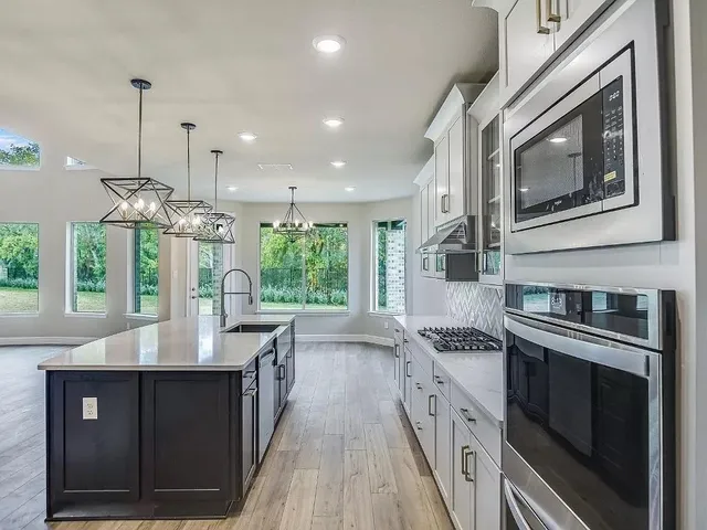 a kitchen with stainless steel appliances granite countertop a stove a sink and a microwave