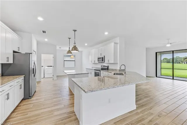 a large kitchen with stainless steel appliances kitchen island a large counter top and a wooden floors