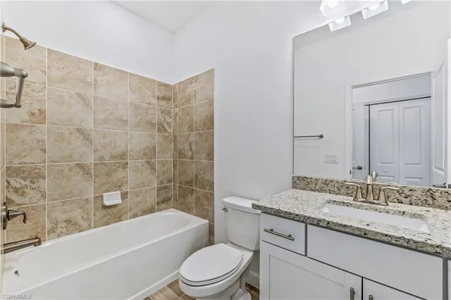 a bathroom with a granite countertop bathtub shower sink vanity mirror and toilet