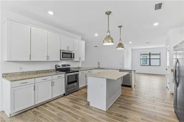 a large kitchen with stainless steel appliances granite countertop a sink a stove and a wooden floors