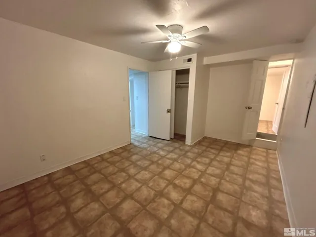 en empty room with windows and chandelier fan