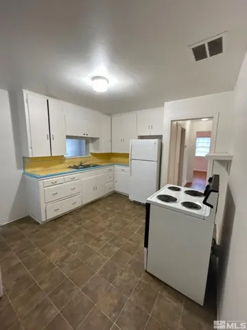 a kitchen with granite countertop a sink a stove a refrigerator and white cabinets