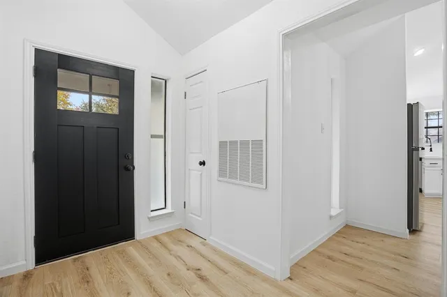 a view of an empty room with wooden floor and a bathroom