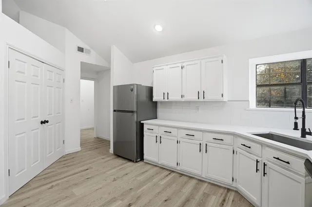 a kitchen with a refrigerator sink and cabinets