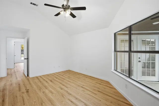 a view of empty room with wooden floor and fan