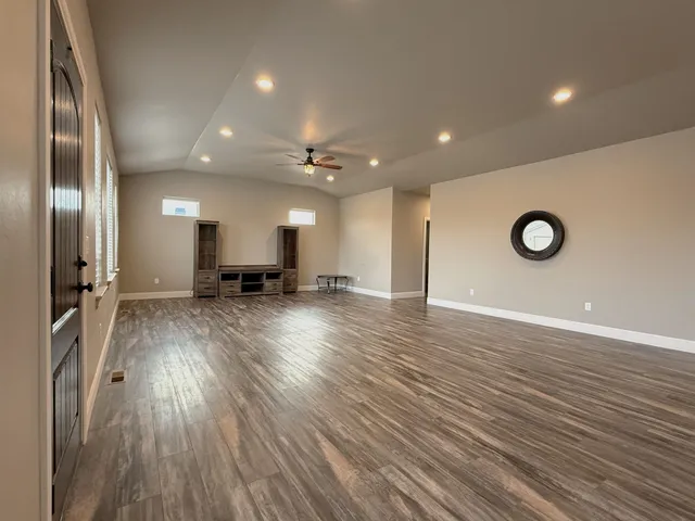 a view of an empty room with window and wooden floor