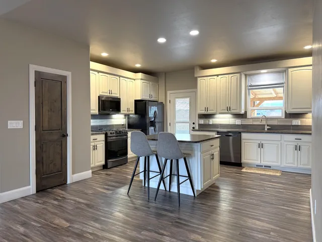a kitchen with stainless steel appliances kitchen island granite countertop a stove a sink and a refrigerator