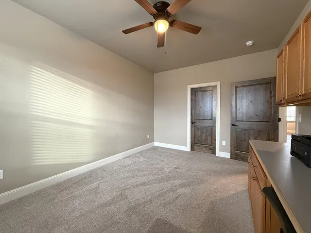 an empty room with windows and fan