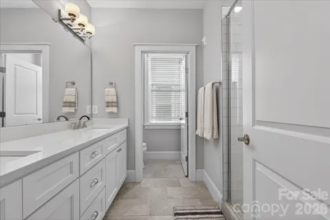a spacious bathroom with a double vanity sink a mirror and a shower