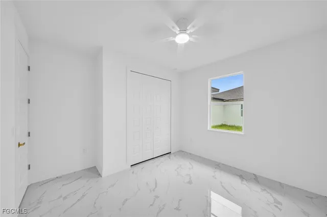 a view of an empty room with a window and kitchen view