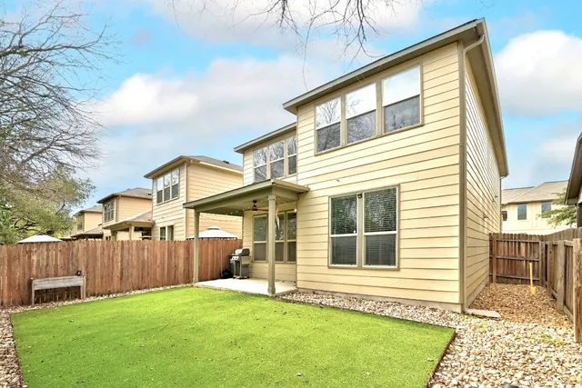 a view of a house with backyard and wooden fence