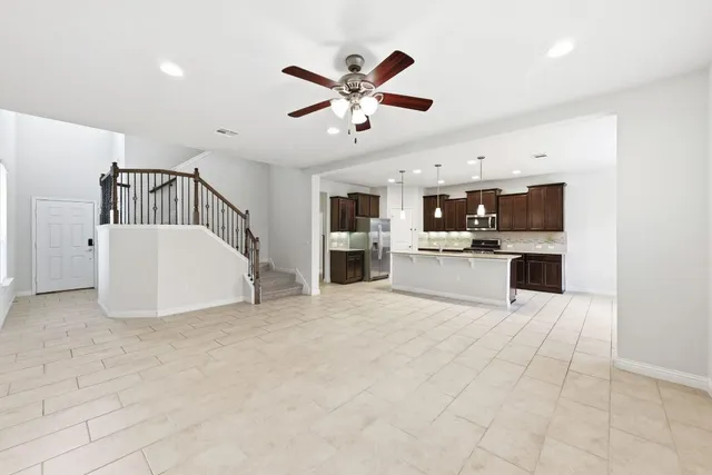 a view of a livingroom with a ceiling fan a kitchen view and a window