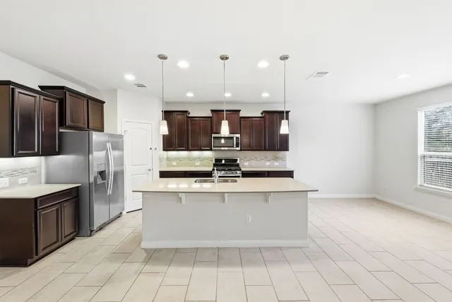 a large kitchen with stainless steel appliances a stove a sink dishwasher and a refrigerator