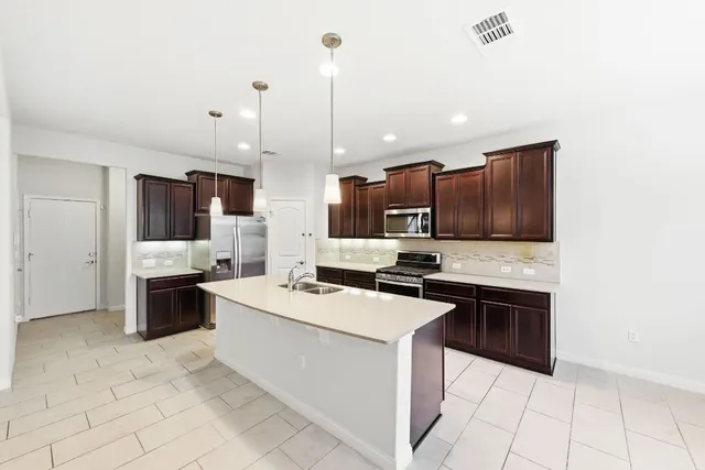 a kitchen with stainless steel appliances a stove top oven a sink a microwave and wooden cabinets