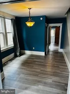 a view of an empty room with window and wooden floor