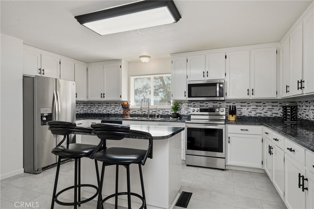 18685 Oak Grove Road Hidden Valley Lake, CA 95467 - Photo 1 of 52 a kitchen with stainless steel appliances granite countertop a stove a sink dishwasher a refrigerator and white cabinets with wooden floor