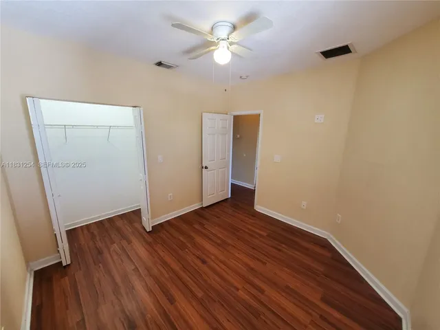 an empty room with wooden floor and a ceiling fan