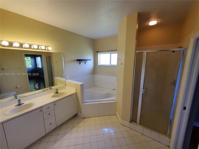 a bathroom with a double vanity sink a mirror and a bathtub