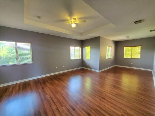 a view of an empty room with window and wooden floor