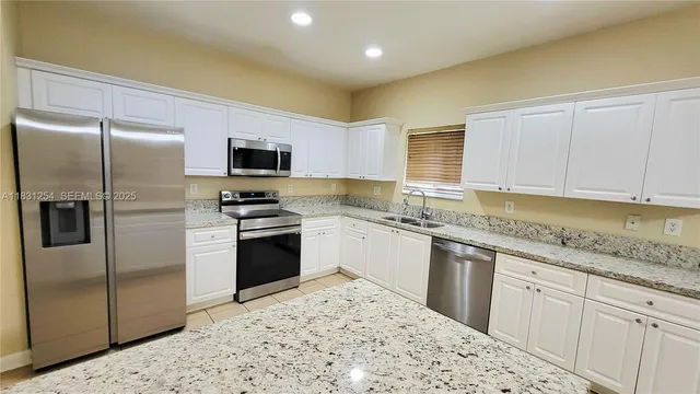 a kitchen with granite countertop a refrigerator and a stove top oven