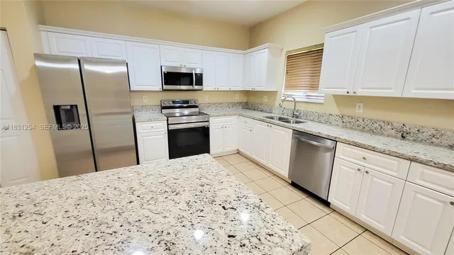 a kitchen with stainless steel appliances granite countertop a refrigerator sink and microwave