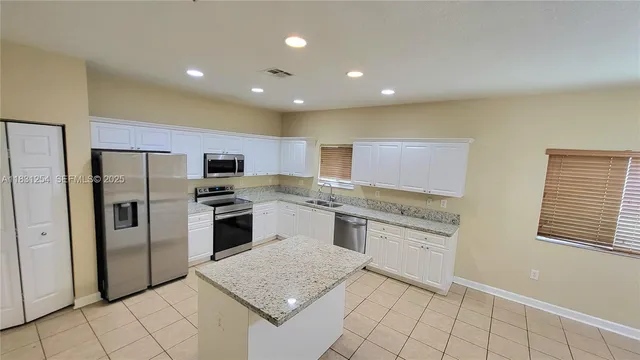a kitchen with stainless steel appliances granite countertop a stove a sink and a refrigerator