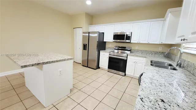 a kitchen with granite countertop white cabinets and stainless steel appliances