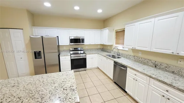 a kitchen with stainless steel appliances granite countertop a refrigerator sink and cabinets