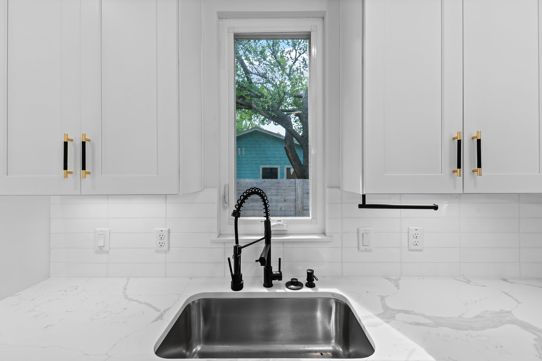 5305 Ledesma Road, Unit 4 Austin, TX 78721 - Photo 6 of 40 A well-lit kitchen features white shaker cabinets and a deep stainless steel sink with modern fixtures.