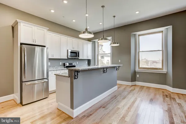 a kitchen with stainless steel appliances granite countertop a refrigerator a sink a stove a microwave and wooden floors