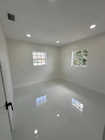 an empty room with windows and ceiling fan