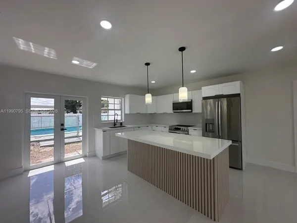 a large kitchen with kitchen island a stove a sink a center island and wooden floor