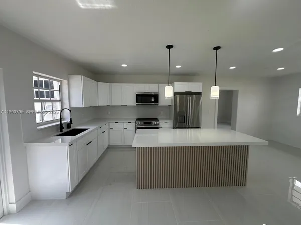 a kitchen with stainless steel appliances granite countertop a sink a stove and a refrigerator