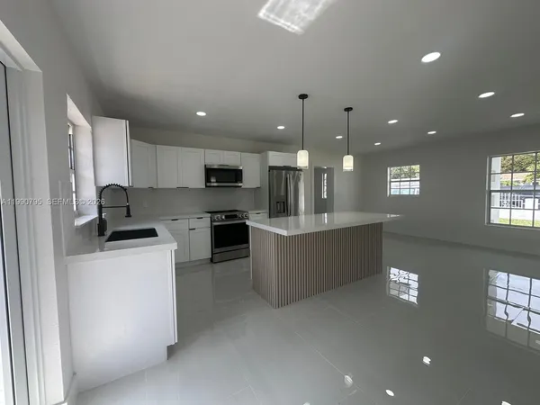 a large kitchen with a large counter top stainless steel appliances and cabinets