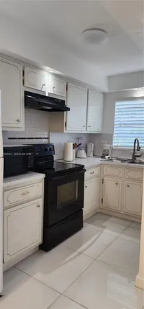 a kitchen with a stove top oven and white cabinets