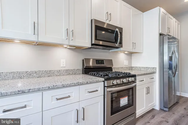 a kitchen with stainless steel appliances granite countertop white cabinets granite counter tops and a stove