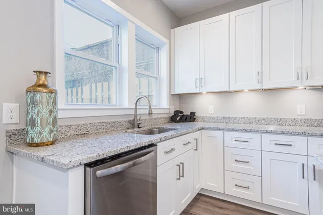 a kitchen with granite countertop white cabinets and sink